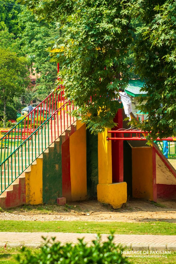 Bold primary colors define this park play structure beneath overhanging trees.